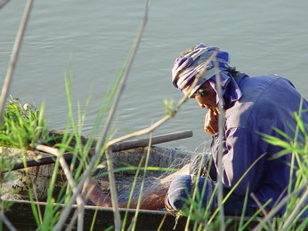 Einbeiniger Fischer am Nam Nguem Fluss repariert sein Fischernetz, nahe Thangone.